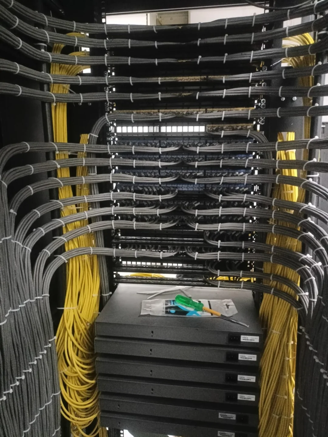 Rear view of grey cable bundles routed into patch panels at Group Surya, Indapur